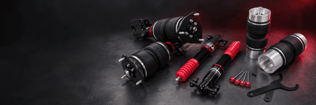 Black air struts, silver-ended air bags and rear dampers with red dust boots on a dark studio workbench
